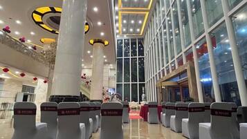 A hotel lobby with rows of seating, large windows, and a high ceiling with circular light fixtures.