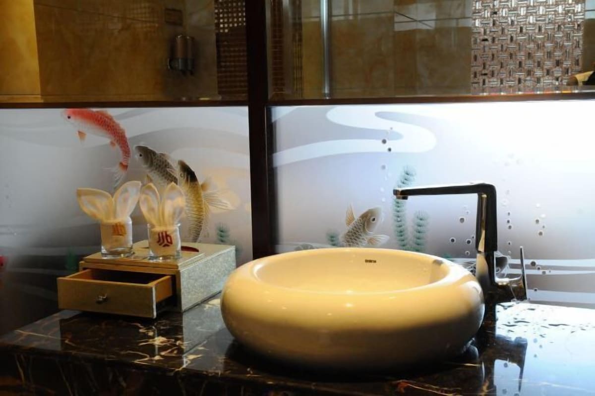 A bathroom with a large vessel sink, a glass partition, and decorative fish.