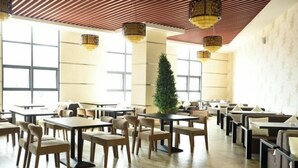 A spacious dining area with multiple tables and chairs, large windows, and hanging lanterns. - Yongqian Hotel (Yongde)