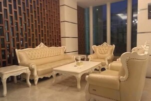 Una habitación con un sofá color beige, un sillón a juego y una mesita.