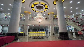 A hotel lobby with a grand chandelier, a reception desk, and a red carpet.