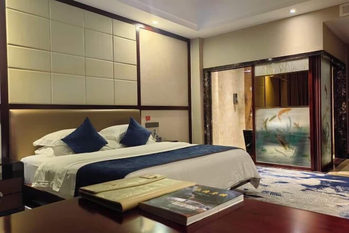 Una habitación de hotel con una cama grande, un escritorio de madera y un cuadro en la pared.