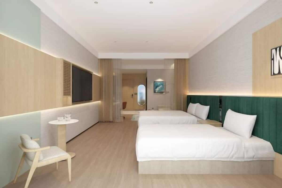 Una habitación de hotel con dos camas, un televisor, una mesita y una silla.
