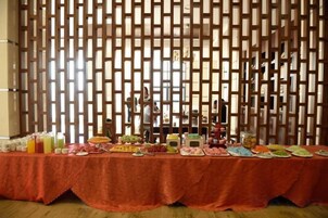Una mesa de buffet con diversos alimentos y bebidas, sobre un fondo decorado.
