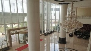 A spacious lobby with high ceilings, large windows, and a grand chandelier. - Yongqian Hotel (Yongde)