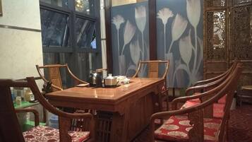 A dining area with a wooden table and chairs, a decorative screen with floral patterns, and a view through a window.