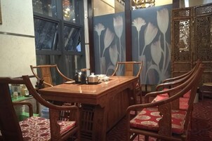 Un comedor con mesa y sillas de madera, un separador decorativo con motivos florales, y vistas por una ventana.