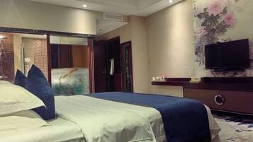A hotel room with a bed, a television, a wall-mounted TV, and a door leading to another room.