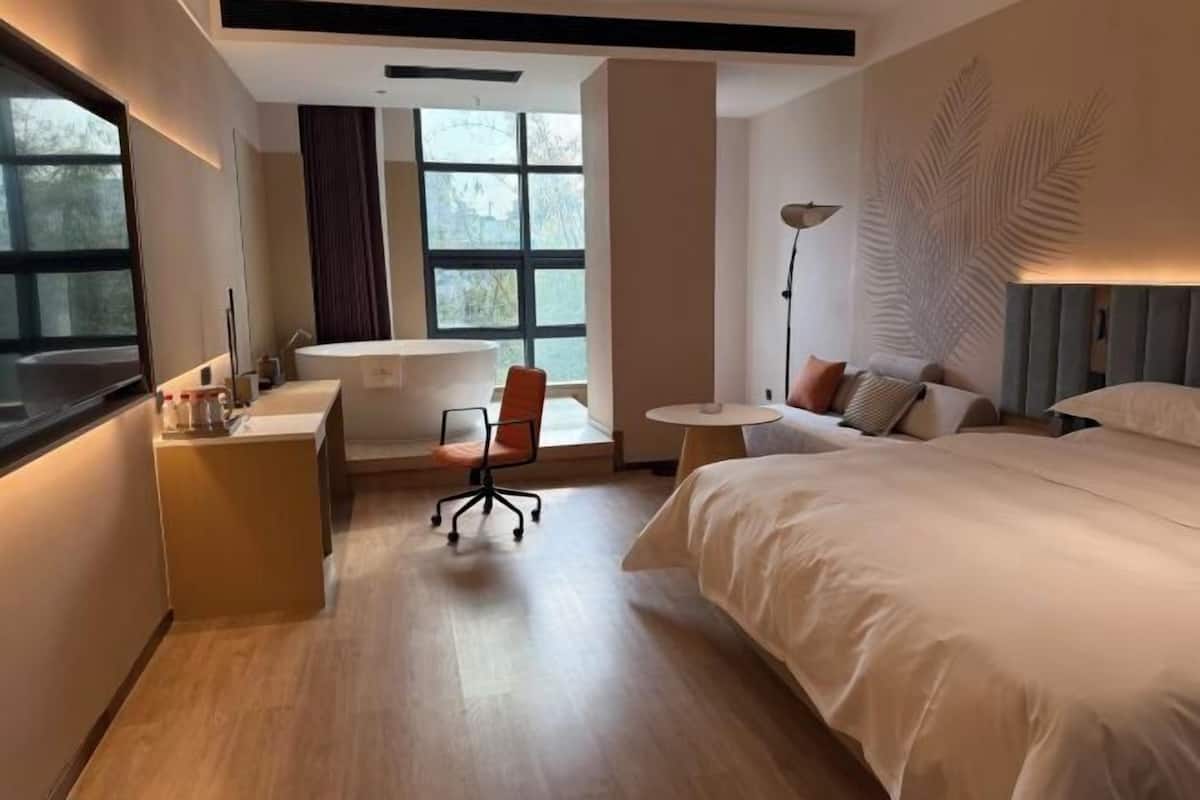 Una habitación de hotel moderna con cama, escritorio, silla y una mesita.
