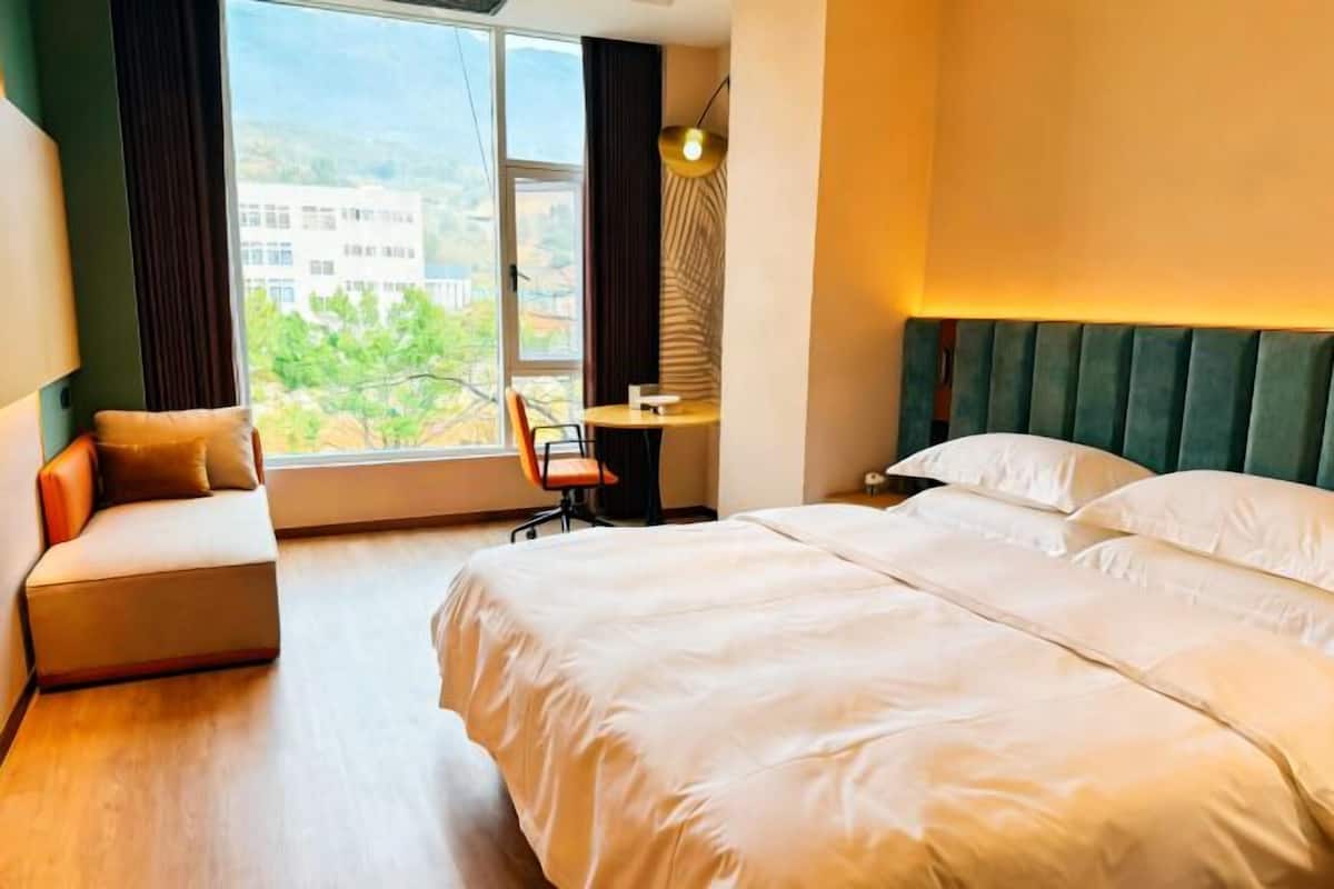 Habitación de hotel con cama, escritorio y vistas a edificios a través de la ventana.