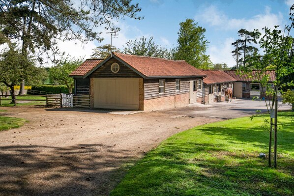 A stable with a dirt driveway and a fenced area.