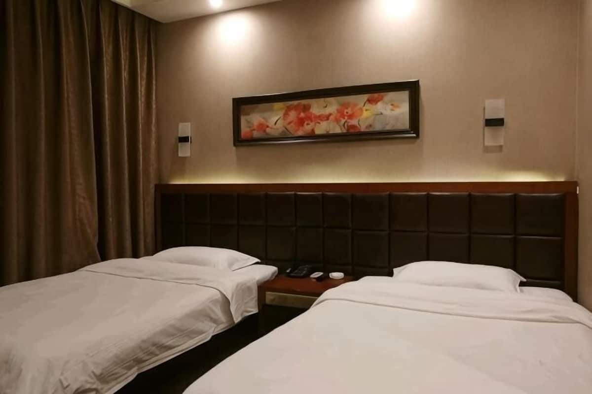 Ein Hotelzimmer mit zwei Betten, einem Kopfteil, einem Gemälde und einem Telefon.