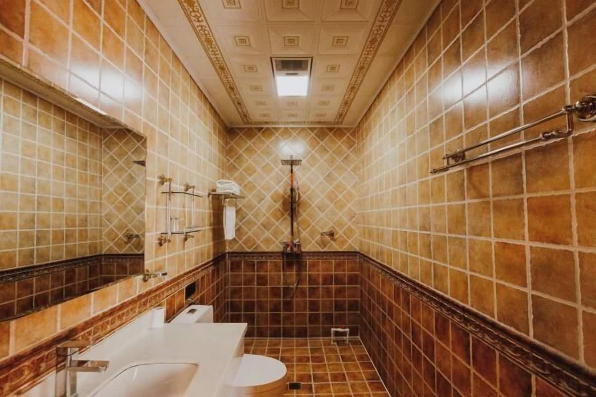 Ein Badezimmer mit einem weißen Waschbecken, einem Spiegel, einem Handtuchhalter und einer Duschkabine.