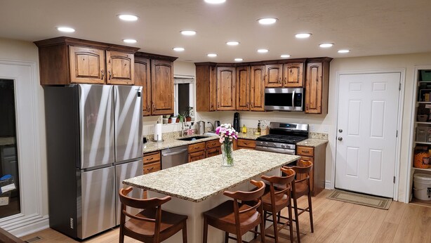 A modern kitchen with wooden cabinets, stainless steel appliances, and a central island with bar stools.