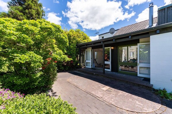 A modern house with a covered patio, a satellite dish, and a garden with various plants and flowers. - Elegant Town House with Wi-Fi, central location, easy walk to town (Taupō)