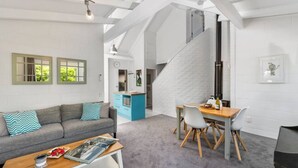 A modern living space with a sofa, dining table, and a staircase leading to an upper level. - Elegant Town House with Wi-Fi, central location, easy walk to town (Taupō)