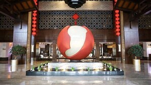 A lobby with a large spherical sculpture, a patterned wall, and a reception desk.