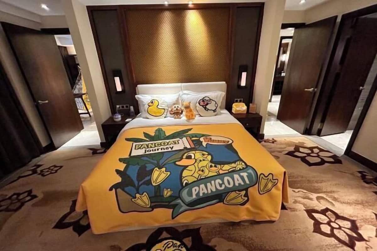 Una habitación de hotel con una cama, una mesita de noche, un espejo y una puerta.