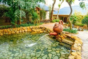A pond with a stone border and a large pot on the edge. - Zhangzhou Longjia Hotel (Zhangzhou)