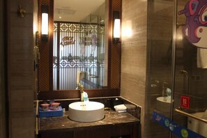 Ein Badezimmer mit einem runden Waschbecken, einem Spiegel und einer Dusche.