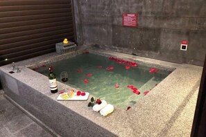 Eine Steineinlage-Badewanne mit Rosenblüten und einer Weinflasche.