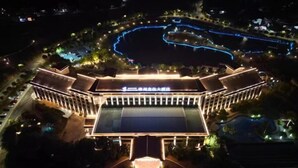 A large, modern hotel with a prominent entrance and a swimming pool.