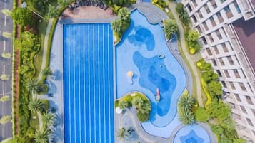 Vista aèria d'una piscina envoltada de vegetació, a tocar d'un edifici.