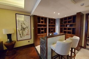 Eine Hotelhalle mit einem Holzbüro, weißen Stühlen, einem großen gerahmten Kunstwerk und integrierten Regalen.