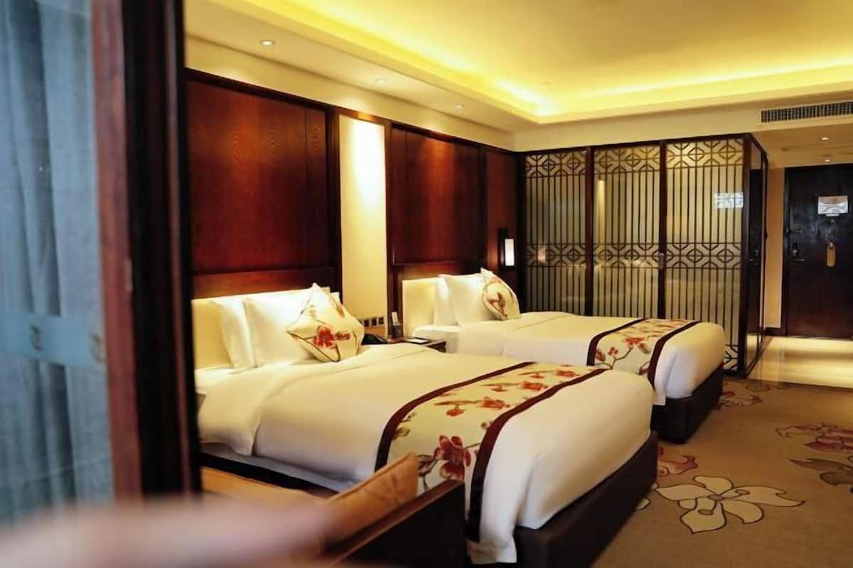 Habitación de hotel con dos camas y cabeceros de madera, además de un separador decorativo.