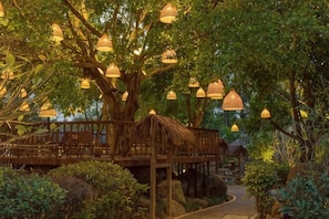 A treehouse with a thatched roof, surrounded by lush greenery and hanging lamps. - Zhangzhou Longjia Hotel (Zhangzhou)