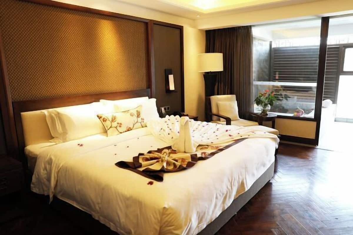 Habitación de hotel con una cama grande, un escritorio, una silla, una l ámpara y una ventana con cortinas.