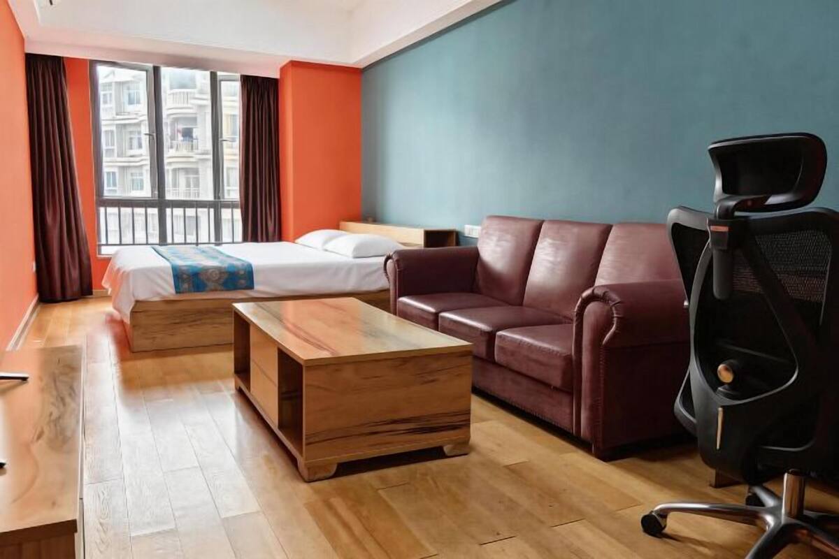 Ein Hotelzimmer mit einem Bett, einer Ledersofa, einem Holztisch und einem schwarzen Bürostuhl.
