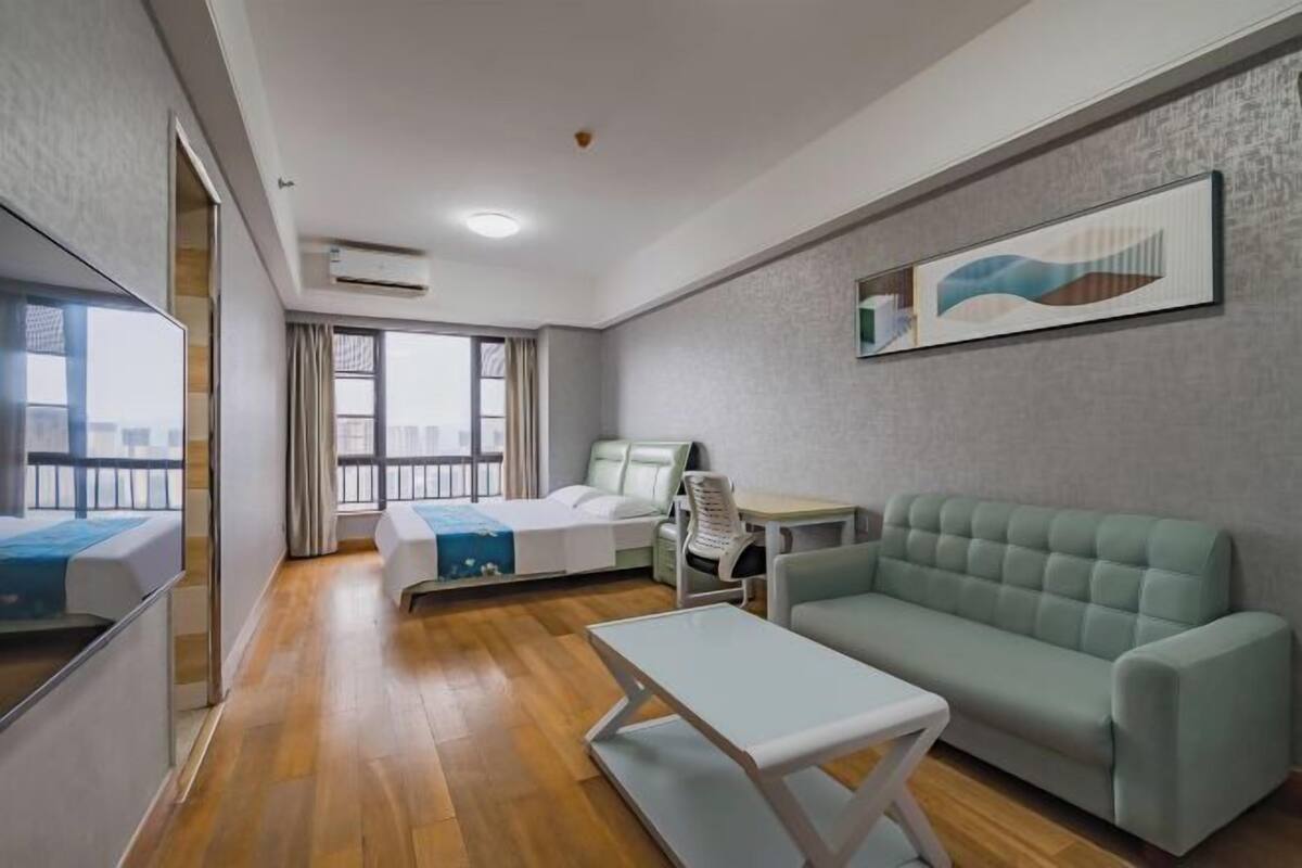 Ein modernes Hotelzimmer mit Bett, Sofa, einem kleinen Tisch und einem Fenster mit Blick.
