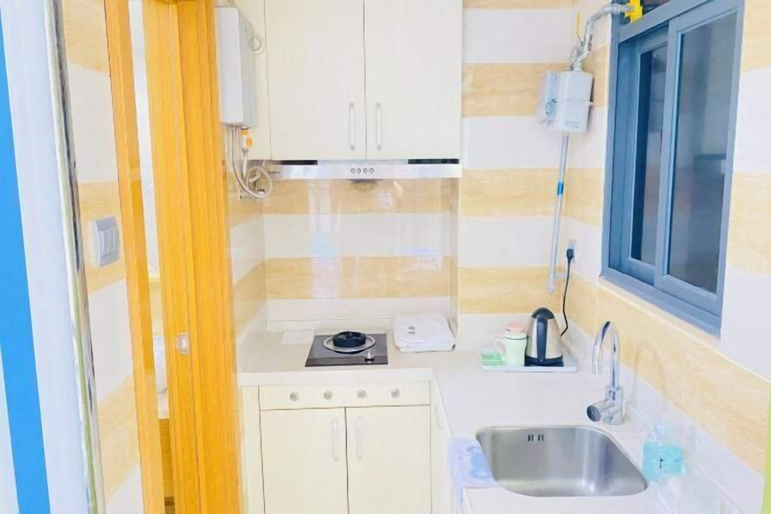 A compact kitchen with a stove, sink, and a window.