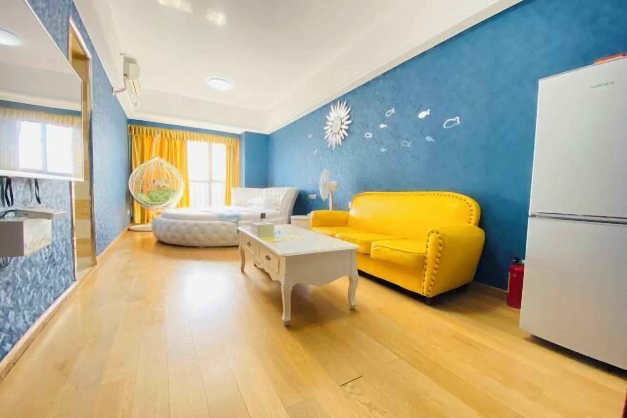 A compact living space with a yellow sofa, a white coffee table, and a hanging chair.