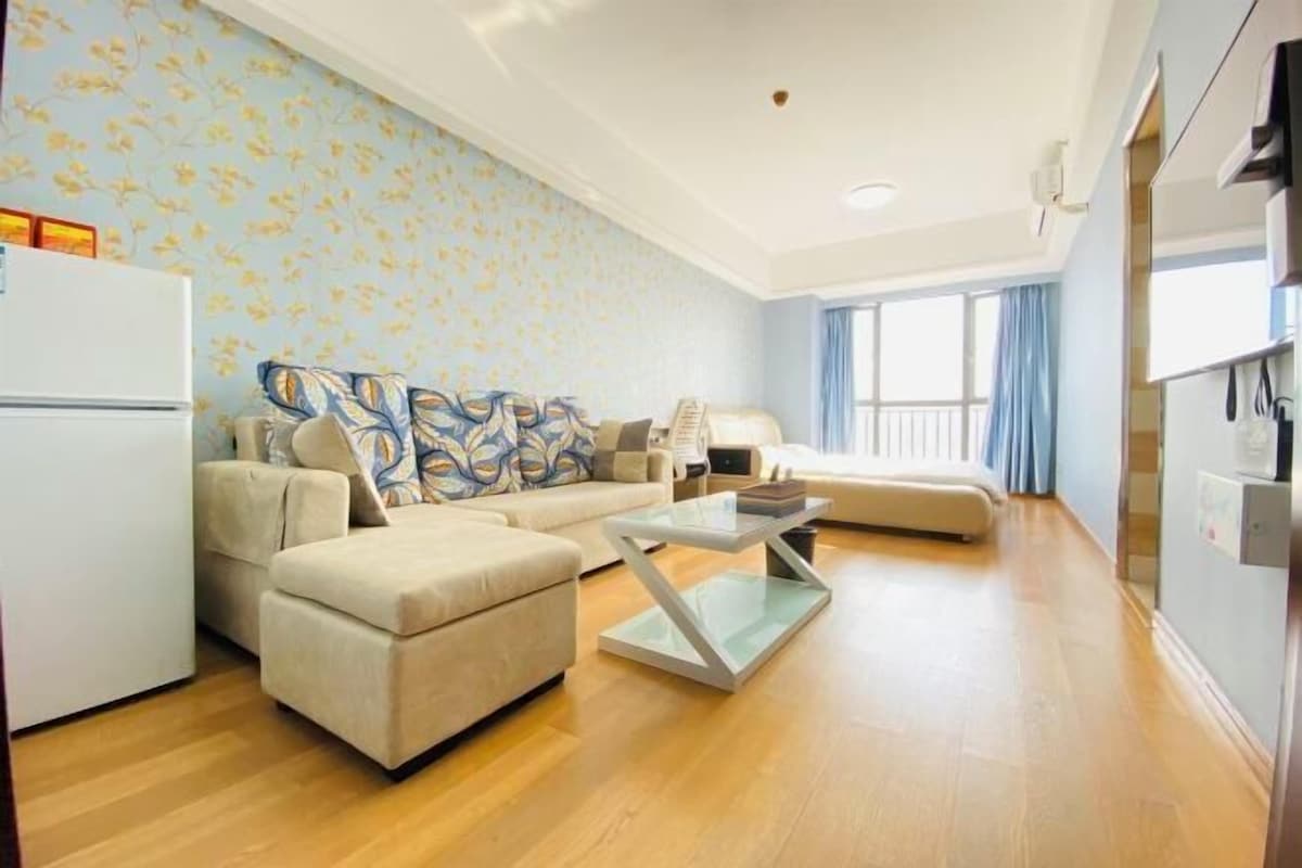 Ein modernes Wohnzimmer mit Sofa, Hocker und Glastisch.
