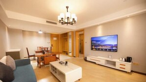 Una sala de estar moderna con un sofá, una mesa de centro, televisor y un comedor con sillas y una mesa.