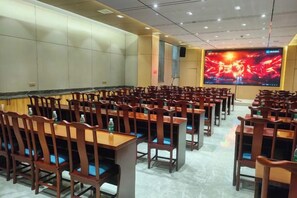 A conference room with rows of wooden tables and chairs, a large screen, and a tiled floor. - Hefu International Hotel (Nanzhang)
