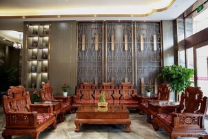 Una recepción de madera tradicional con un amplio panel decorativo, arreglos de asientos y una planta en maceta.