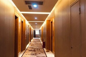 A hotel hallway with wooden doors, recessed lighting, and a patterned carpet. - Hefu International Hotel (Nanzhang)