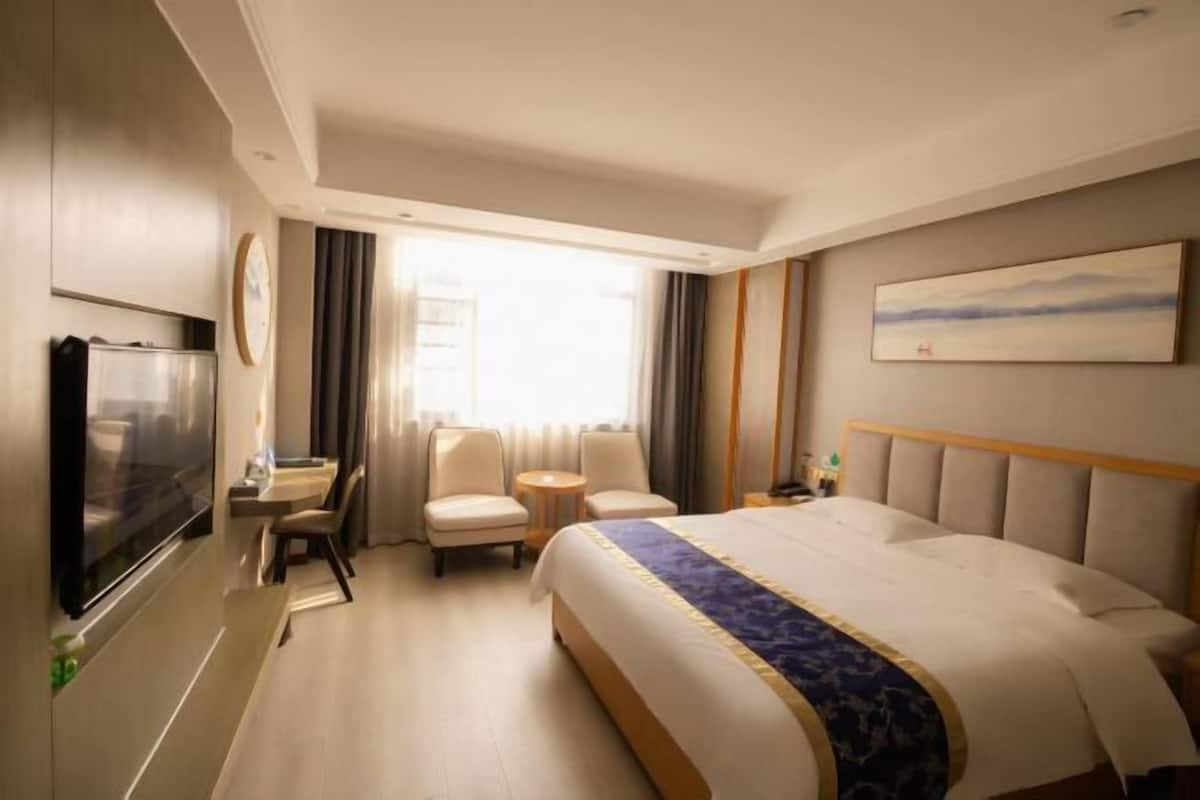 Ein Hotelzimmer mit Bett, Fernseher, Schreibtisch und Stuhl.