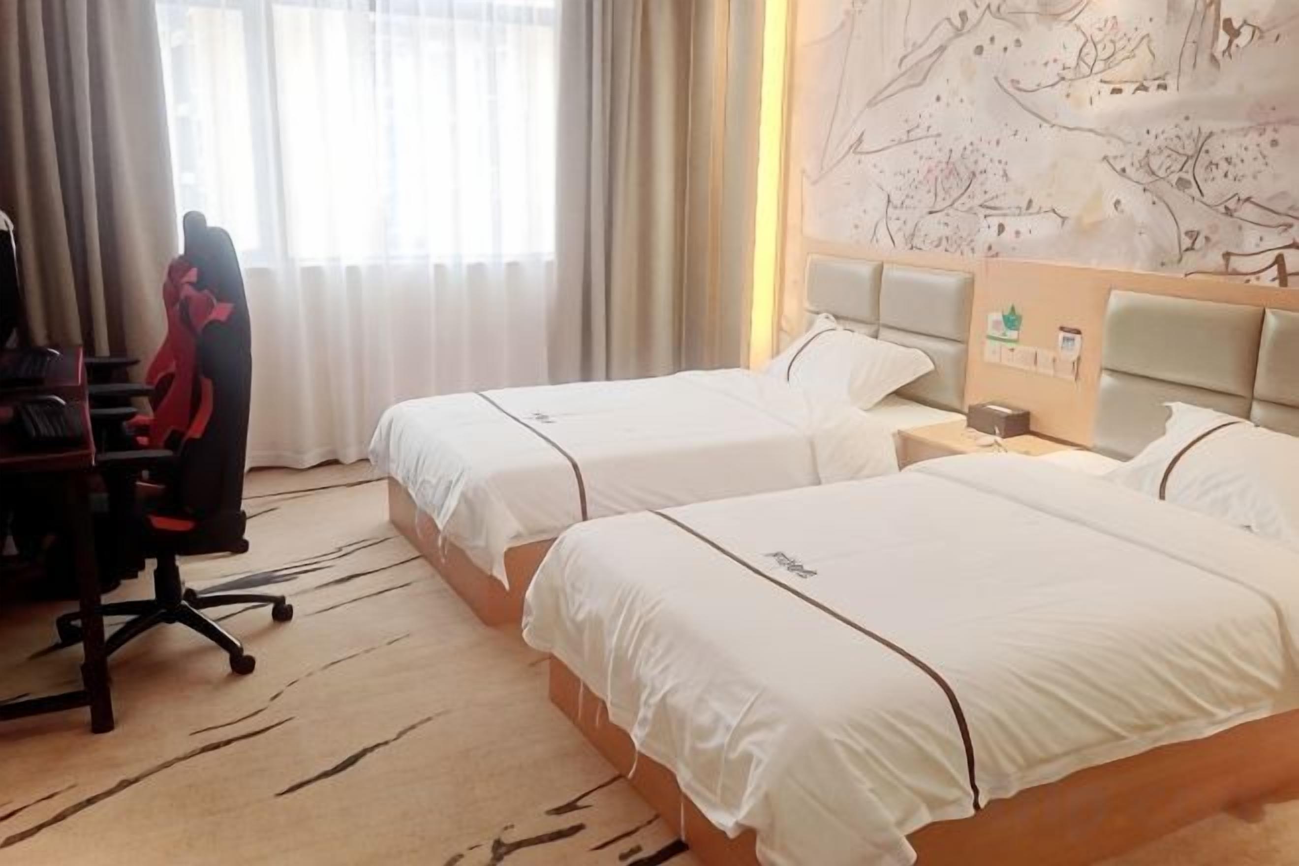 A hotel room with two beds, a desk with a chair, and a nightstand with a lamp.