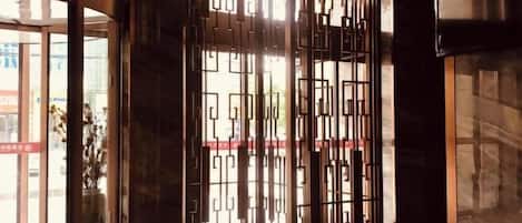 A modern interior with a geometric metal partition, a glass door entrance, and a stone wall.
