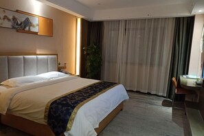 A hotel room with a large bed, a desk, and a chair. - Hefu International Hotel (Nanzhang)