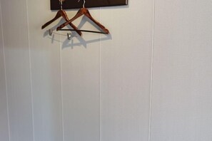 Un mur sur lequel sont fixés deux porte-manteaux en bois, suspendus à une tige métallique.