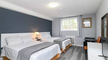 A hotel room with two beds, a desk, a chair, a TV, and a window with curtains.