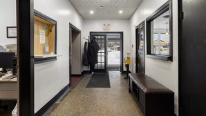 Un couloir avec un banc, un porte-manteau et une porte donnant sur une sortie.