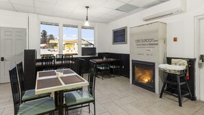 Un espace repas avec des tables et des chaises, une cheminée et une vue sur l’extérieur.