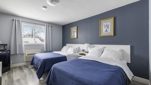 Une chambre d’hôtel avec deux lits, un bureau, un four à micro-ondes et une fenêtre avec des rideaux.