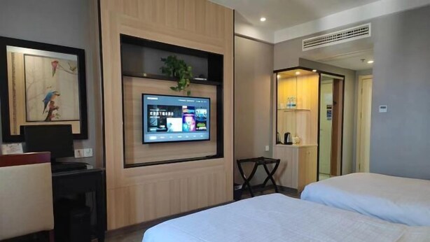Una camera d'albergo con un letto, una scrivania, un televisore a parete e un tavolino.